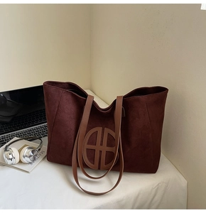 Detail of burgundy suede tote bag with leather straps on office desk with laptop
