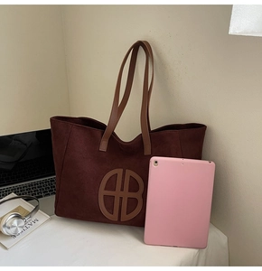 Detail of dark brown tote bag capacity shown with a pink tablet and books