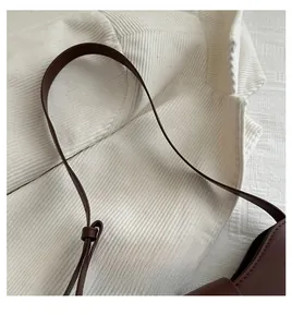 Detail der braunen Kunstledertasche mit geknotetem Griff und feiner Handnahtverzierung
