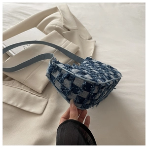 Détail du sac à bandoulière en denim à carreaux avec bords effilochés et sangle