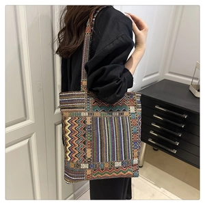 Detail of colorful woven tote bag with geometric patterns worn by a model in interior