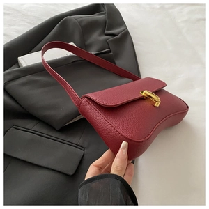 Close-up of burgundy lychee leather bag with a gold buckle on black and white fabric