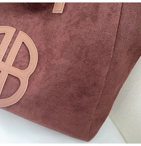 Detailed close-up of textured suede tote bag featuring unique leather logo stitching
