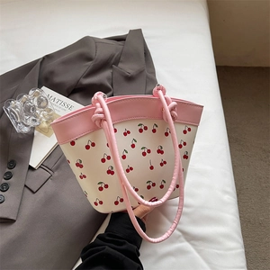 Minimalist cherry print crossbody bag with pink knotted handles and creamy white base