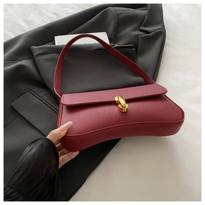 Detail of burgundy lychee leather shoulder bag with golden metallic twist lock closure