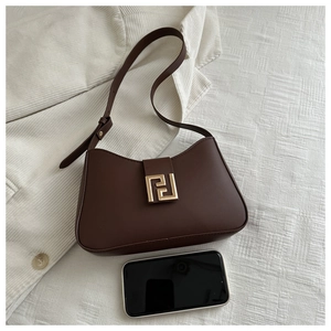 Detailansicht der kaffeebraunen Ledertasche mit goldener Schnalle und Handy zum Größenvergleich