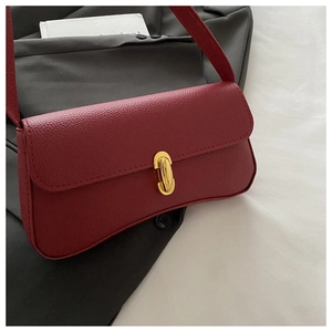 Detail of burgundy lychee grain leather handbag featuring a gold oval twist lock closure