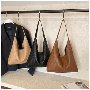 Three woven hobo bags in beige, black and tan colors displayed on a metal hanger stand