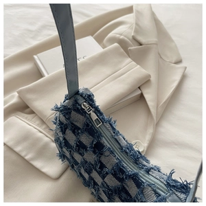 Détail du sac à bandoulière en denim à carreaux bleu et blanc avec bords effilochés et zip