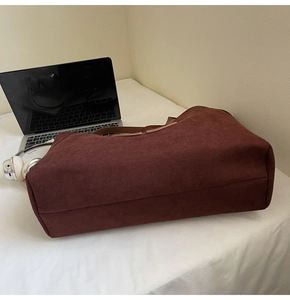 Detail showing the burgundy suede texture and brown leather handles of the tote bag