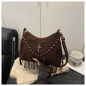 Detail of brown suede shoulder bag featuring metal studs, cross charm and long tassels