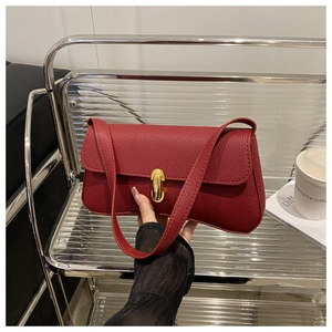 Close-up of deep red lychee textured leather underarm bag with gold metal twist lock