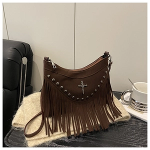 Detailed macro view of brown suede shoulder bag with long fringes and metal cross charm