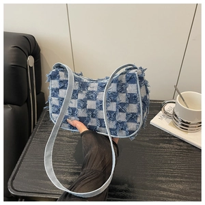 Détail du sac baguette en jean à carreaux bleus et blancs avec bords effilochés et sangle