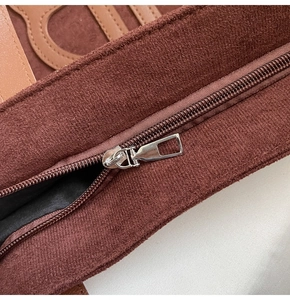 Macro detail of high-quality metal zipper and stitching on a dark brown suede tote bag