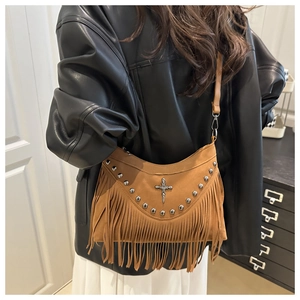 Detail of a brown suede fringed crossbody bag with silver studs and metal dagger charm