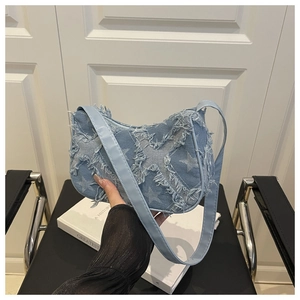 Détail du sac baguette en jean bleu clair avec motifs d'étoiles et bords effilochés