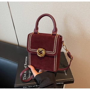 Détails d'un sac à main en daim rouge foncé avec fermoir doré et rivets stylés
