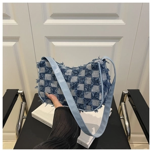Detail of denim checkered shoulder bag with frayed edges and light blue leather strap