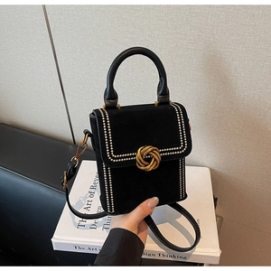 Détail du sac bandoulière en daim noir avec rivets dorés et fermoir rotatif circulaire