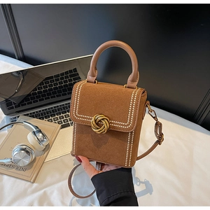 Détail d'un sac bandoulière en daim marron avec boucle nœud dorée et coutures contrastées