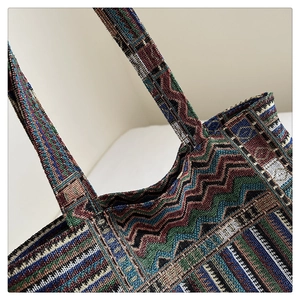 Detail shot of multicolor woven tote bag showing wavy ethnic patterns and stitched handle