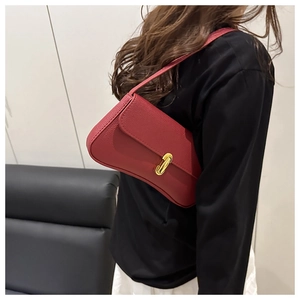 Detail of red pebbled leather underarm bag featuring a metallic gold rectangular twist lock