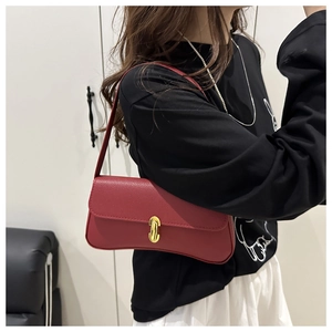 Side view of red grainy leather underarm bag with gold oval buckle worn by model