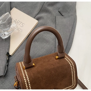 Détail du sac à main en daim marron avec broderie de blé dorée et finitions métalliques