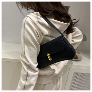 Detail shot of a black pebbled leather baguette bag with a gold metal clasp buckle