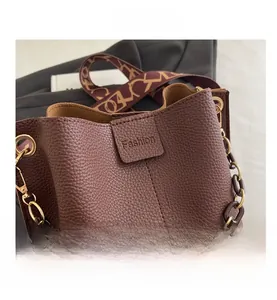 Detail view of brown lychee grain leather bucket bag with fashion embossed logo and chain