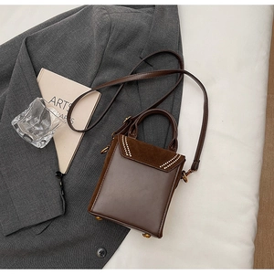 Détail du sac à main marron en cuir avec rabat en daim, cristaux et pieds dorés