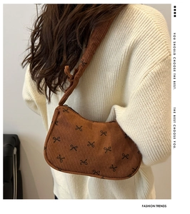 Brown corduroy shoulder bag featuring black bow patterns and knotted strap detail