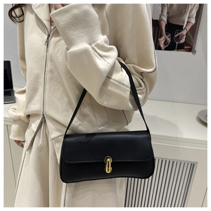 Detail of black lychee grain leather handbag with elegant gold metal twist-lock buckle