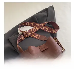 Detailed close-up of brown pebbled leather bucket bag with geometric fabric shoulder strap