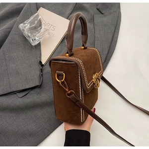 Détail du sac vintage en daim marron avec surpiqûres blanches et boucle dorée