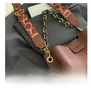 Detail of brown litchi leather bucket bag with resin chain and patterned fabric strap