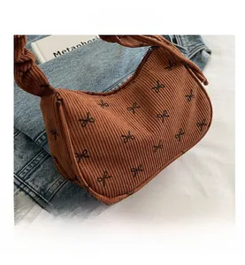 Close-up of brown corduroy hobo bag with black bow prints and gathered handle detail