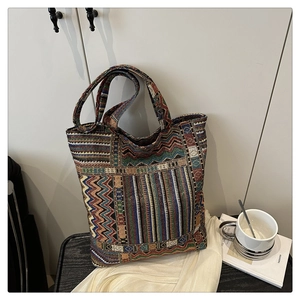 Detailed side view of an ethnic embroidered canvas tote bag on a modern table setup