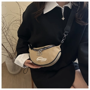 Detail of beige canvas half-moon crossbody bag with embroidered logo and black nylon strap