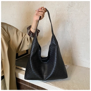 Detail of black woven texture large Hobo tote bag held by a model in soft daylight