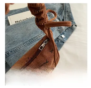 Detail of brown corduroy shoulder bag featuring black bow patterns and smooth silver zipper