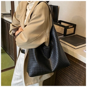 Macro shot of black woven faux leather tote bag showing high-quality craft texture