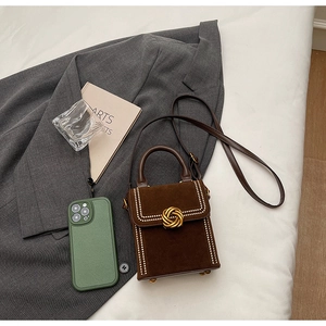 Détail d'un mini sac en daim marron avec bordure perlée et fermoir pivotant doré chic