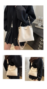 Close-up of off-white bucket bag with litchi texture and adjustable shoulder straps