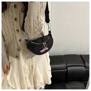 Detail of black nylon crescent crossbody bag with pink embroidery and adjustable strap
