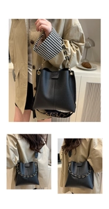Detail of black textured leather bucket bag with gold chain and patterned strap