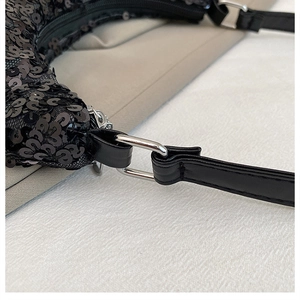 Detailed macro view of black sequin texture and silver metal buckle on the shoulder strap