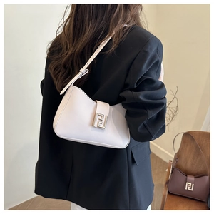 Detailansicht der cremeweißen Schultertasche mit Metallschnalle getragen an einem Model