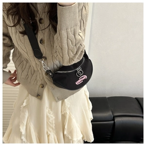 Close-up of black nylon crescent bag with pink embroidery and silver round zippers